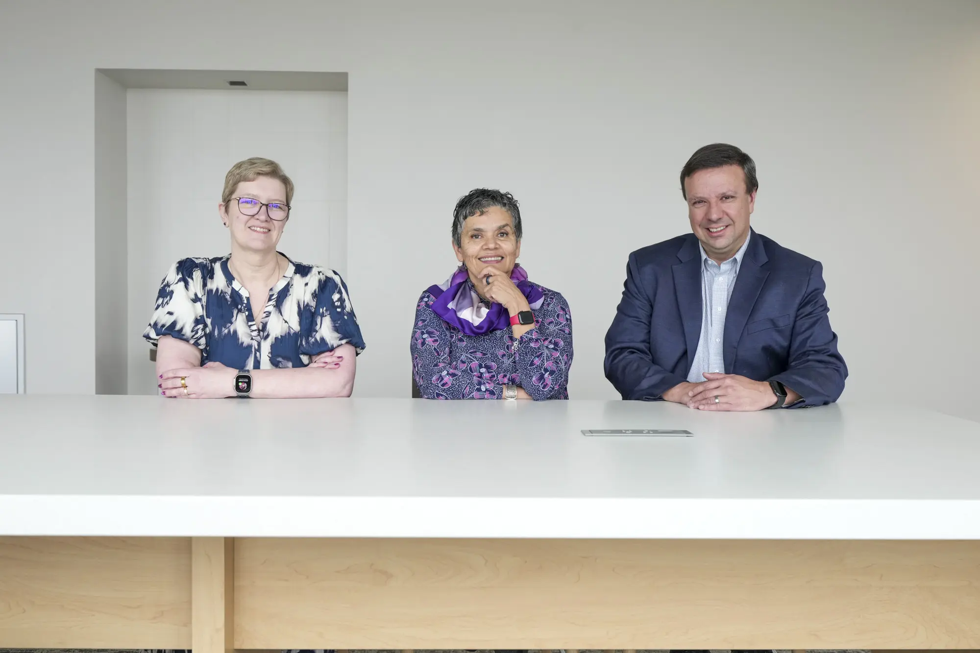 Donna Wilcock, Malu Tansey and Jason Meyer sit together at a long white table