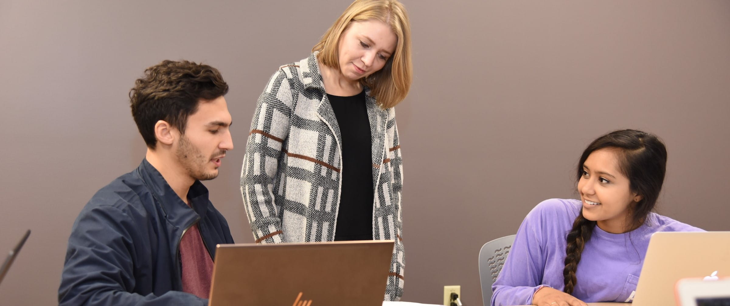 a faculty member and students work together in a classroom in evansville