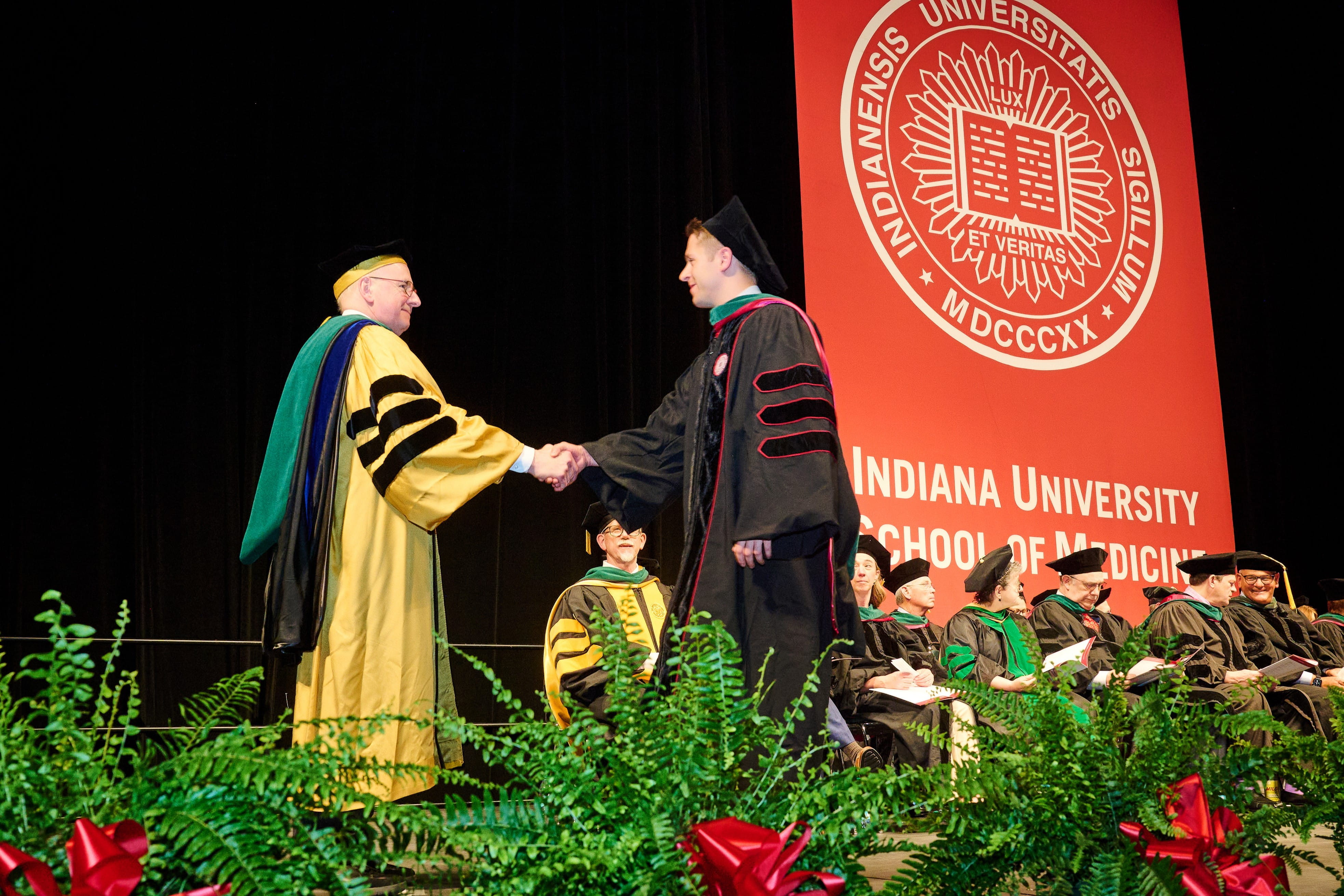 A graduate of the Class of 2024 shakes hands with Jay Hess,MD, PhD, MHSA