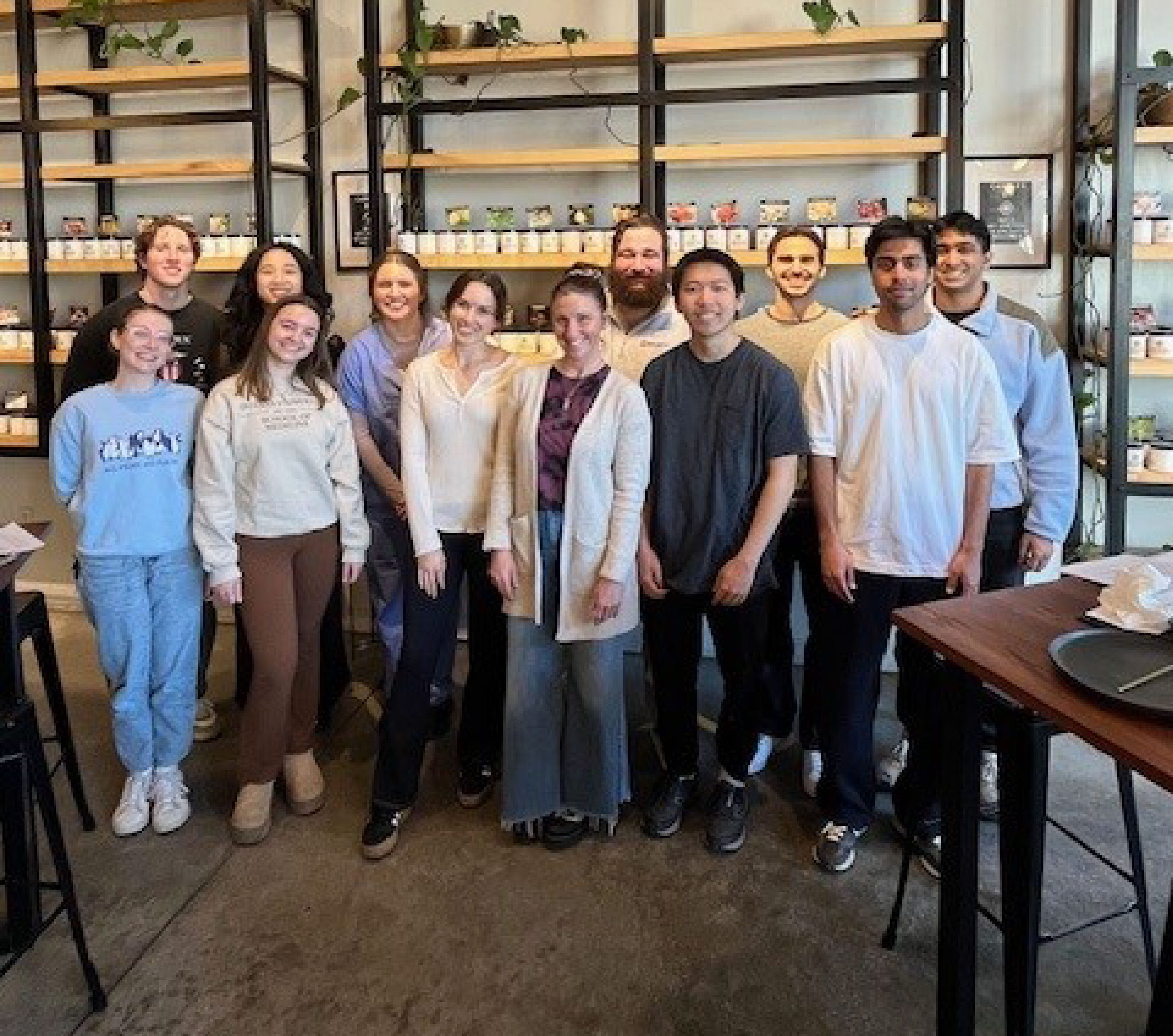 The members of the Wellness Coalition gather in a modern shop with shelves behind them