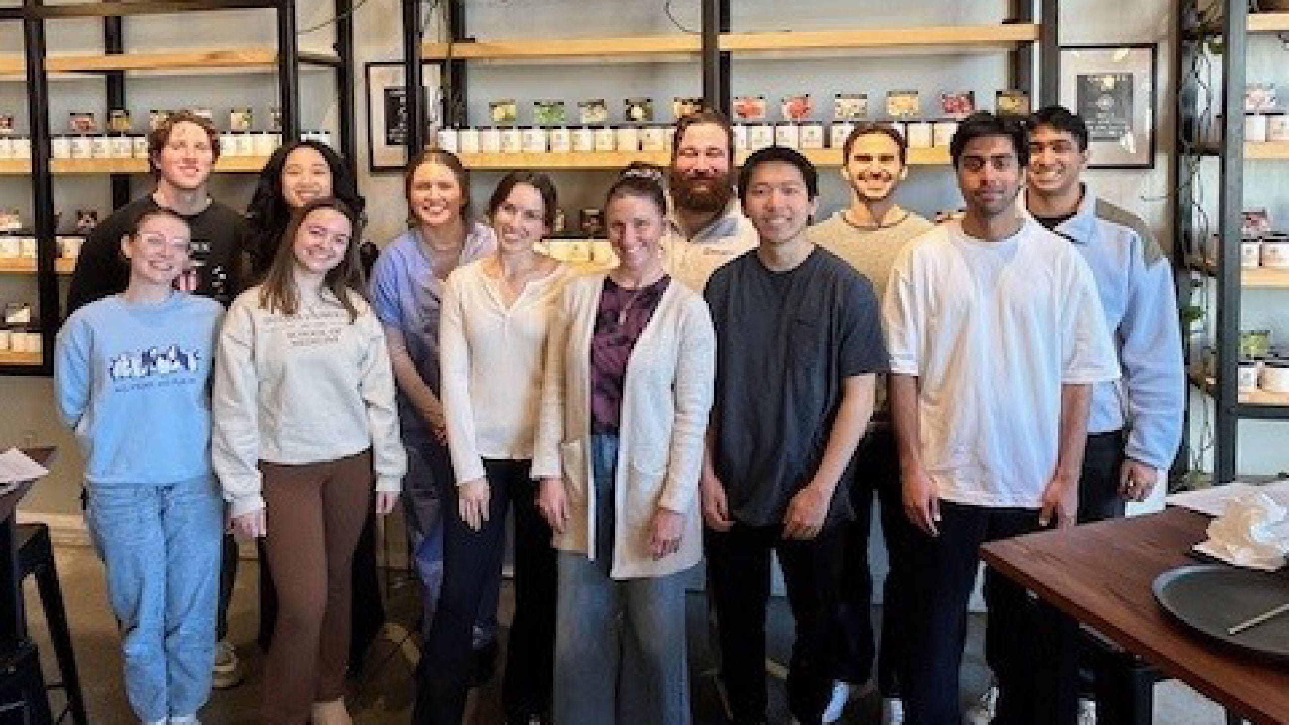 The members of the Wellness Coalition gather in a modern shop with shelves behind them