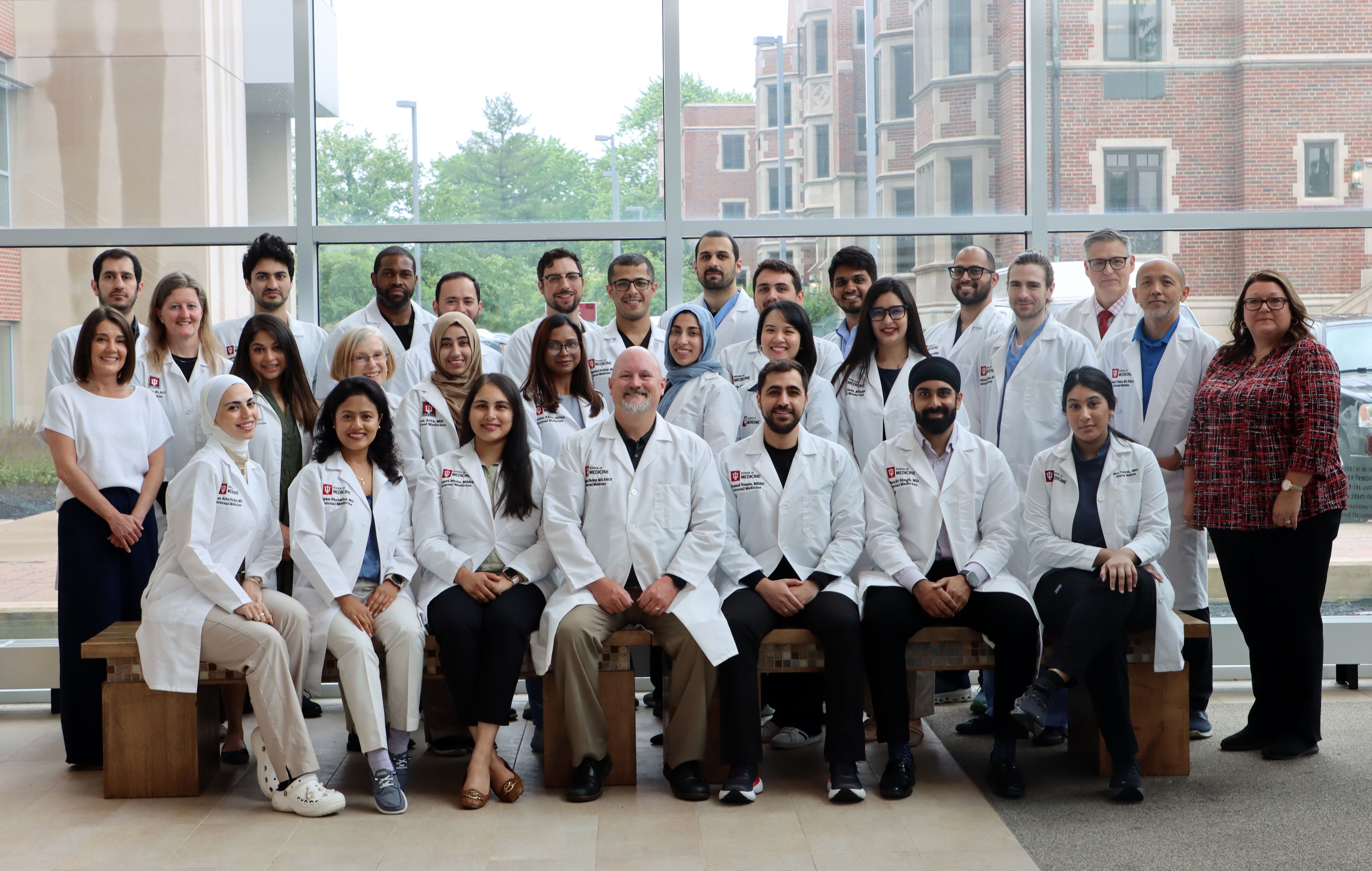 About 20 young doctors in white coats stand together and smile. These are members of the he Internal Medicine Residency program in Muncie, Indiana for the 2024-25 academic year.