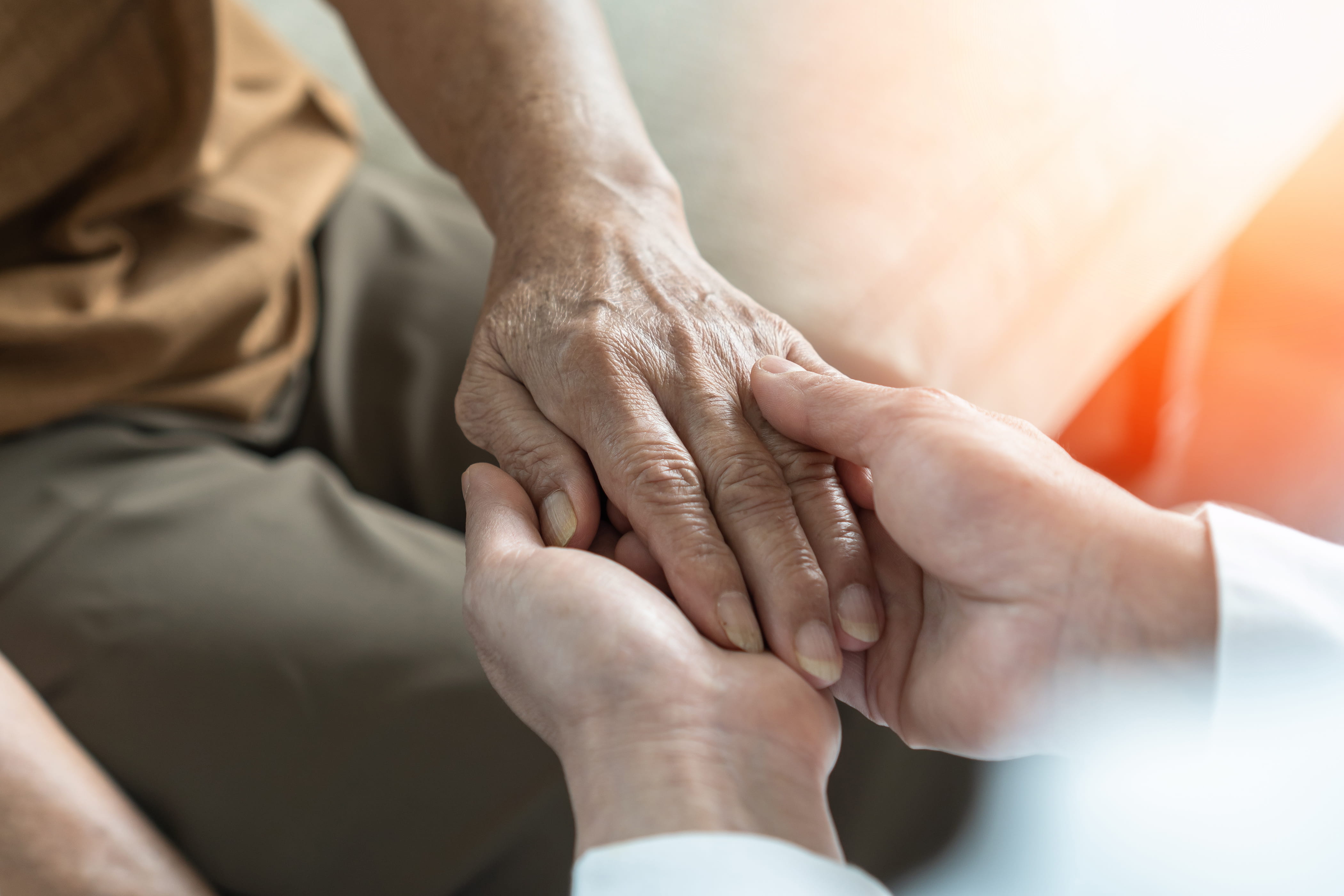 close up photo of a person's hand being held in support by a caregiver