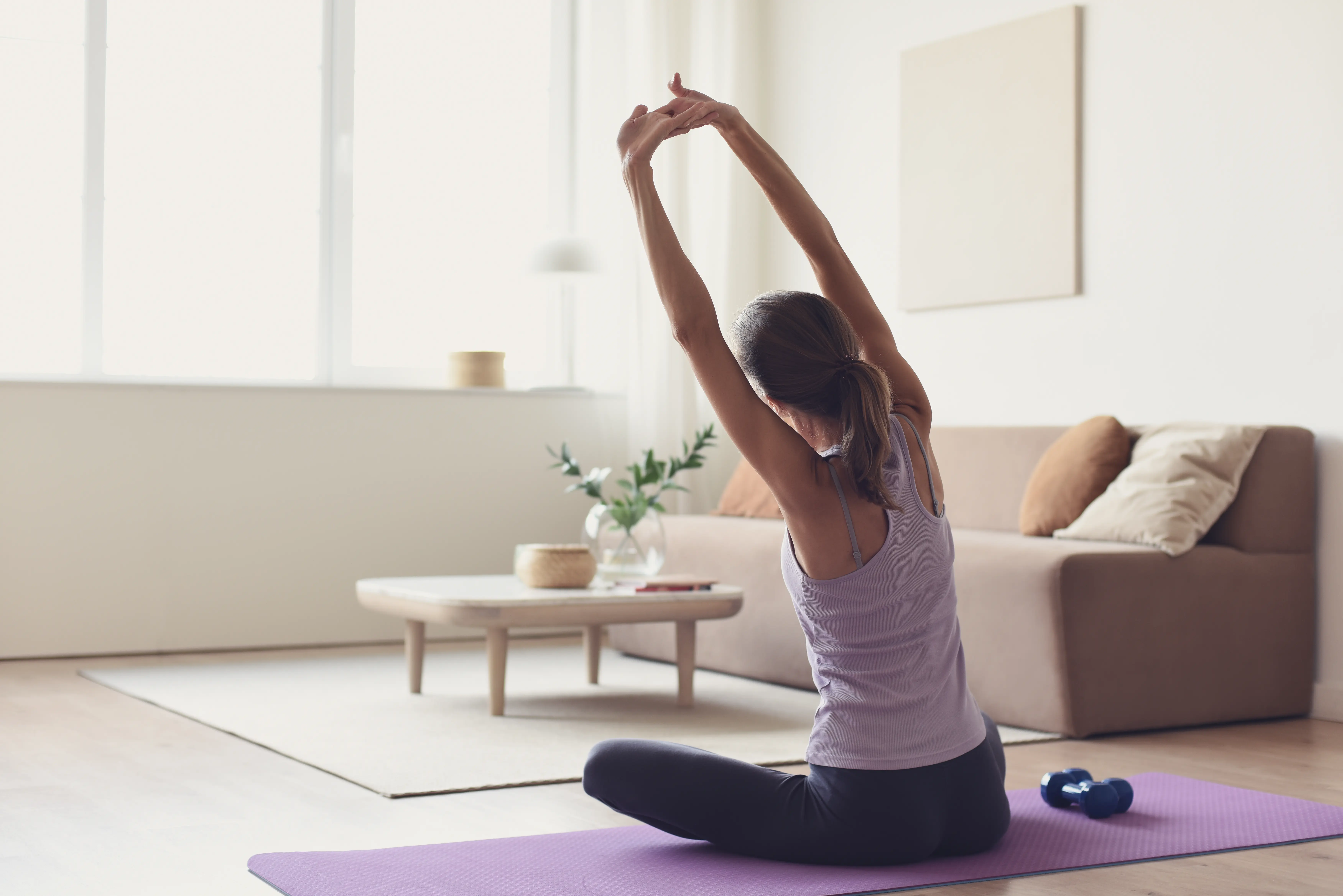 A woman stretches on a purple mat. 