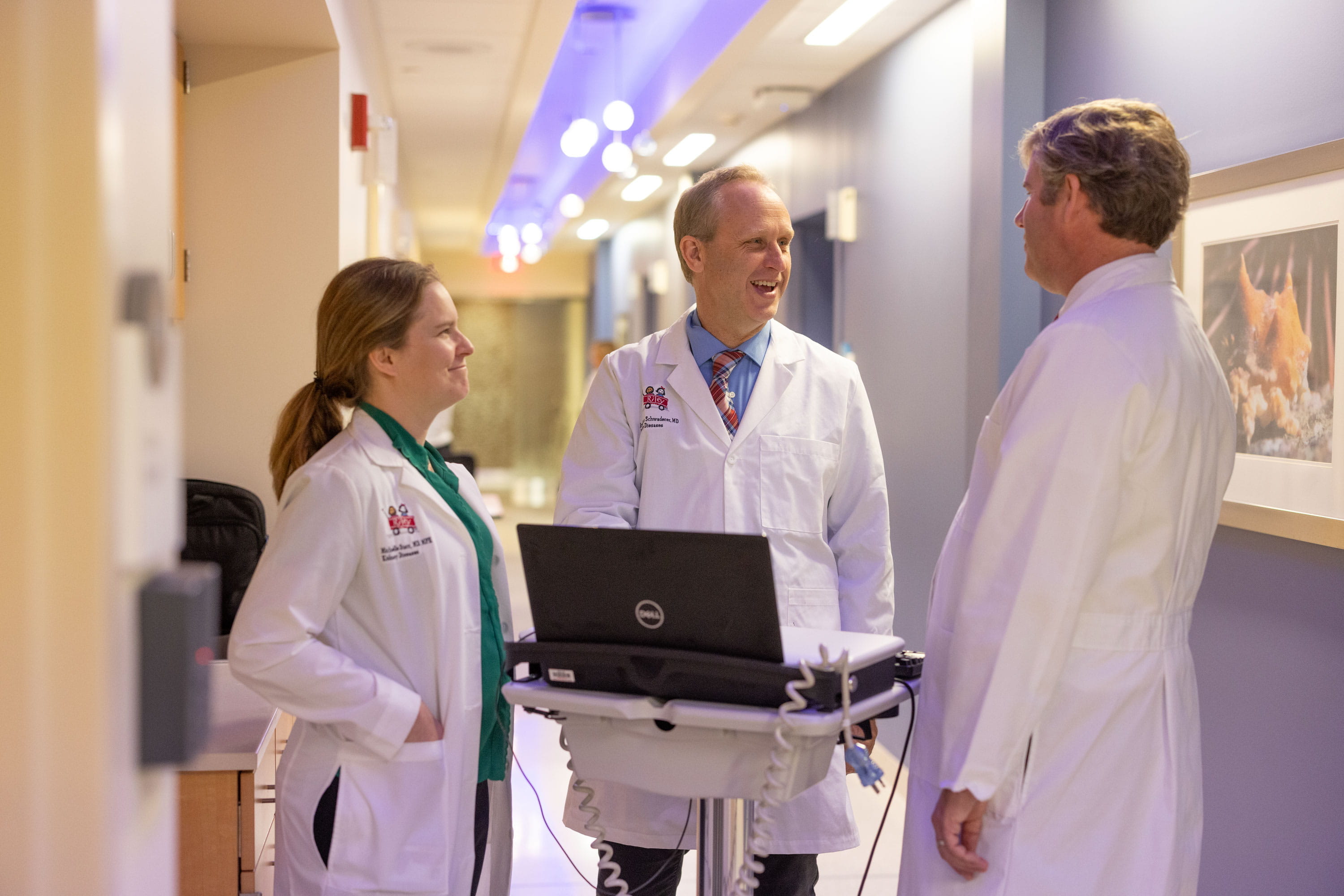 Researchers wearing white coats talk in the hallway