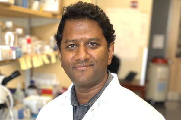 headshot of Arupratan Das in white coat in lab 