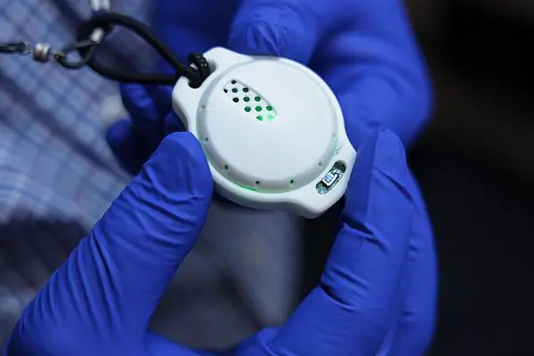 person with gloves on holding breathalyzer device  