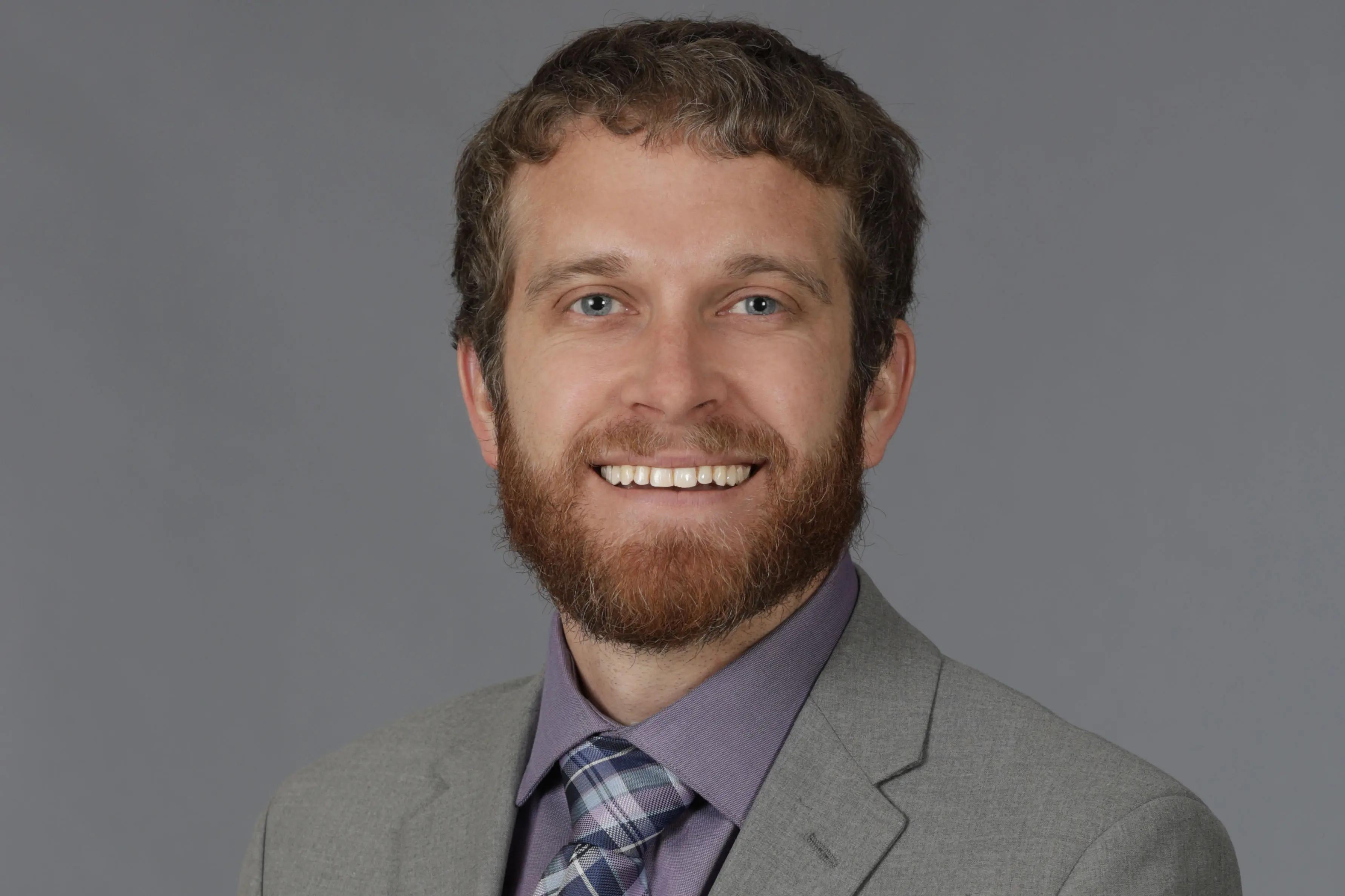 A man in a suit smiles. 
