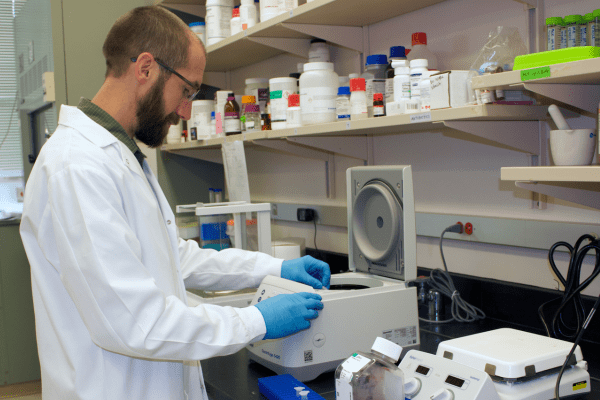 A man in white coat works in a laboratory. 
