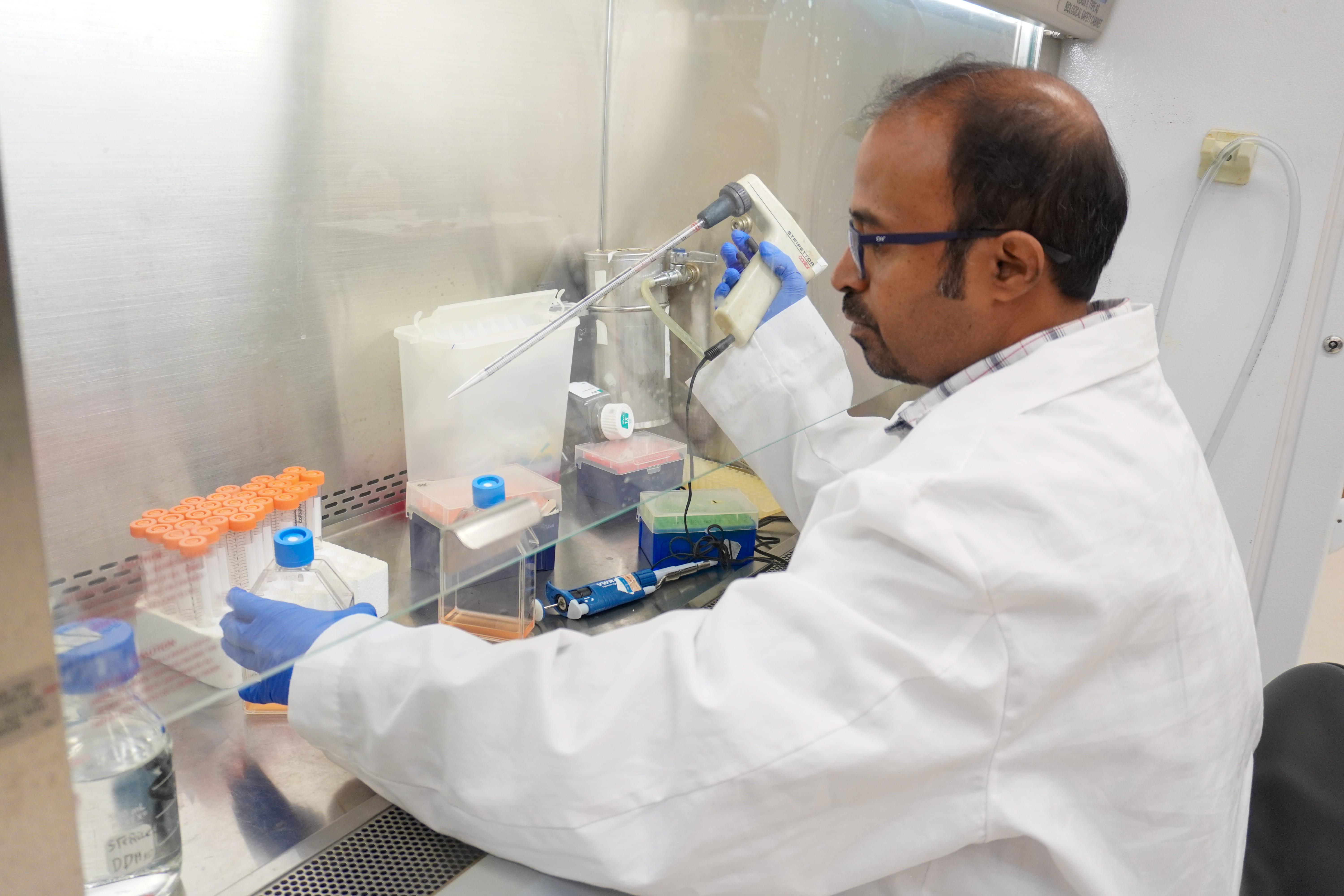 A seated man working in a laboratory setting. 