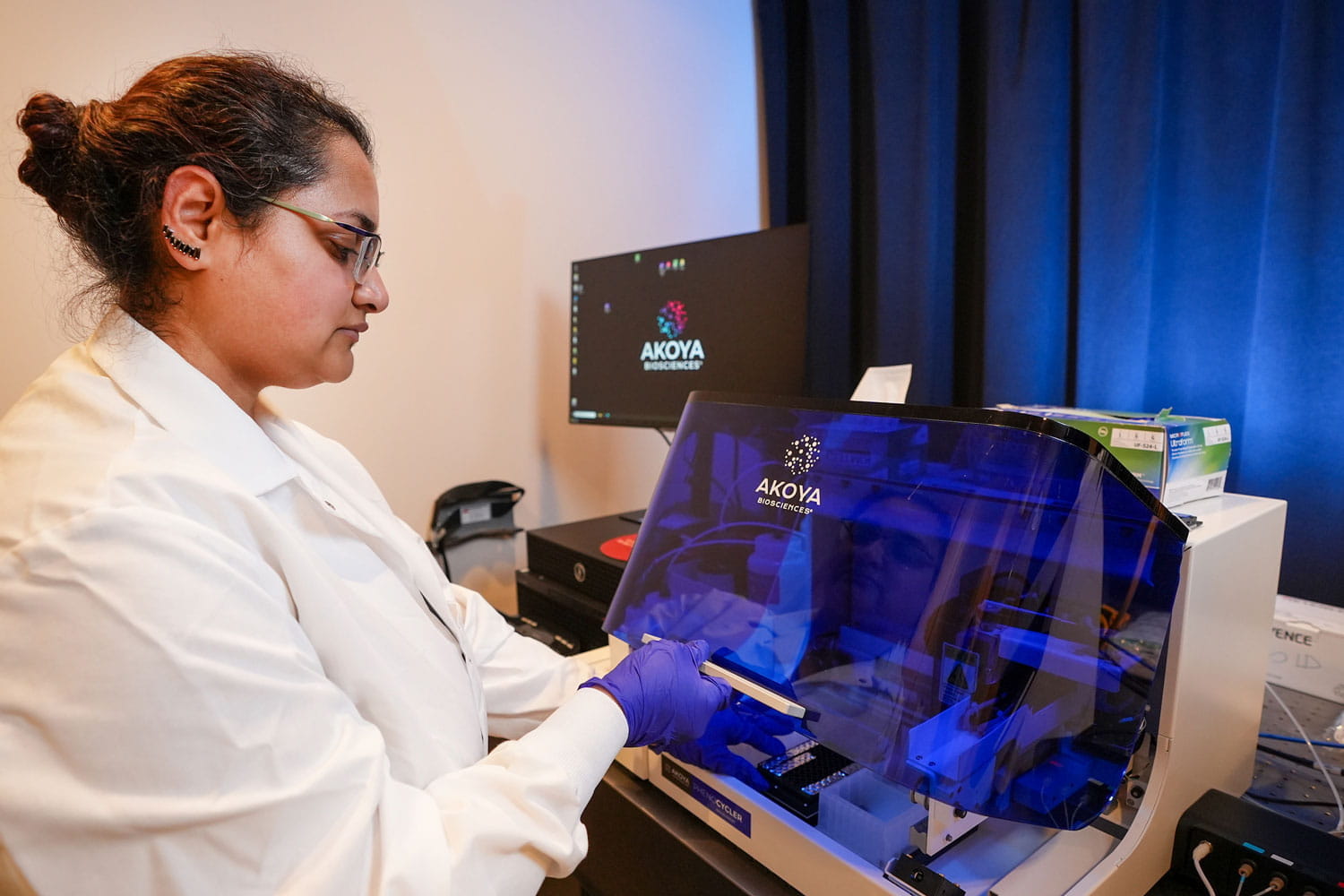 A woman in a white coat uses lab equipment. 