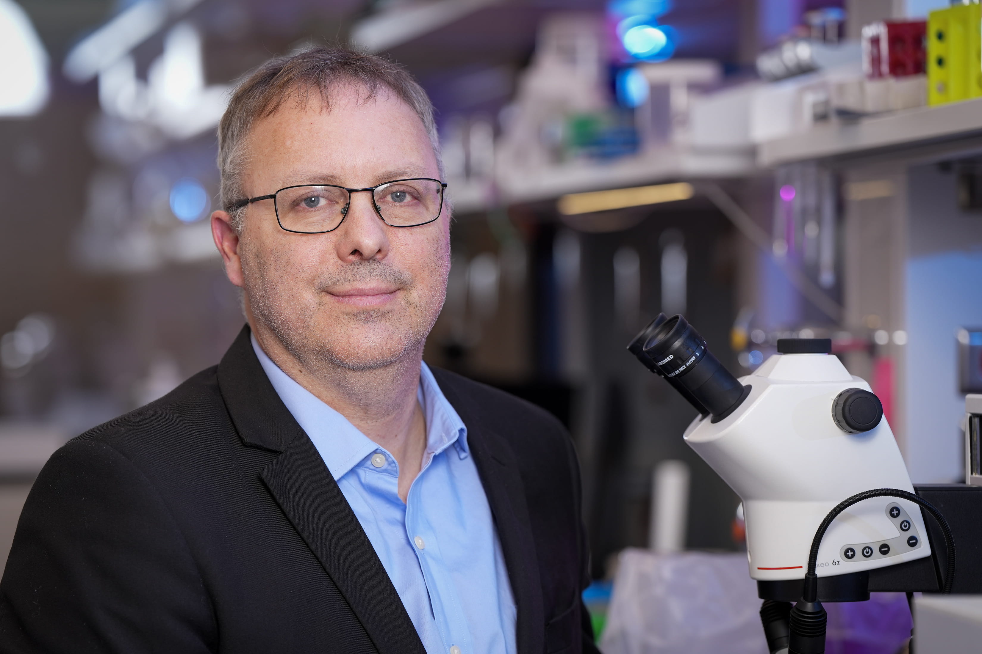 A man poses with a microscope. 