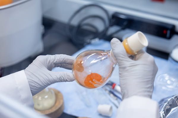 A bottle holds an orange liquid in a chemistry lab. 