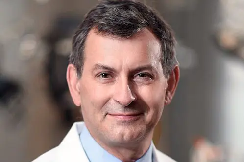 A headshot of a man in a lab coat