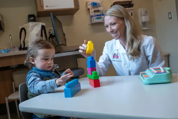 A researcher plays with a child at a table. 