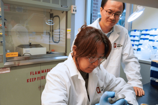 two scientists in lab coats looking in lab
