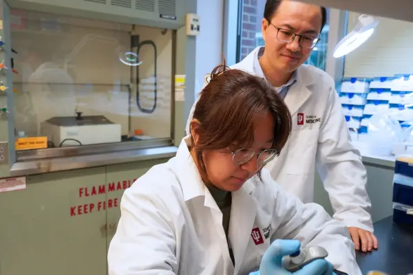 two scientists in lab coats looking in lab