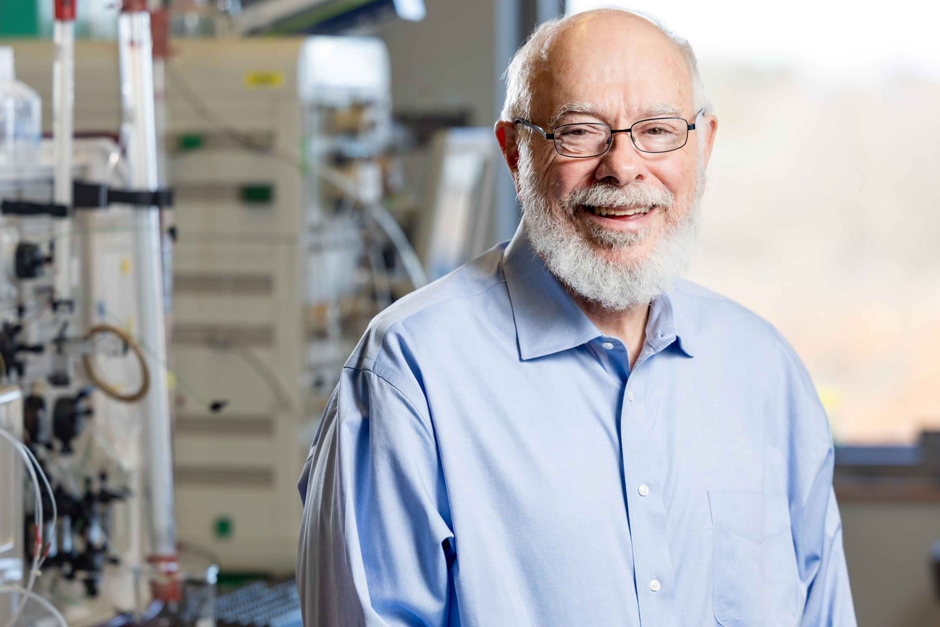 A man in a blue shirt poses in his lab. 