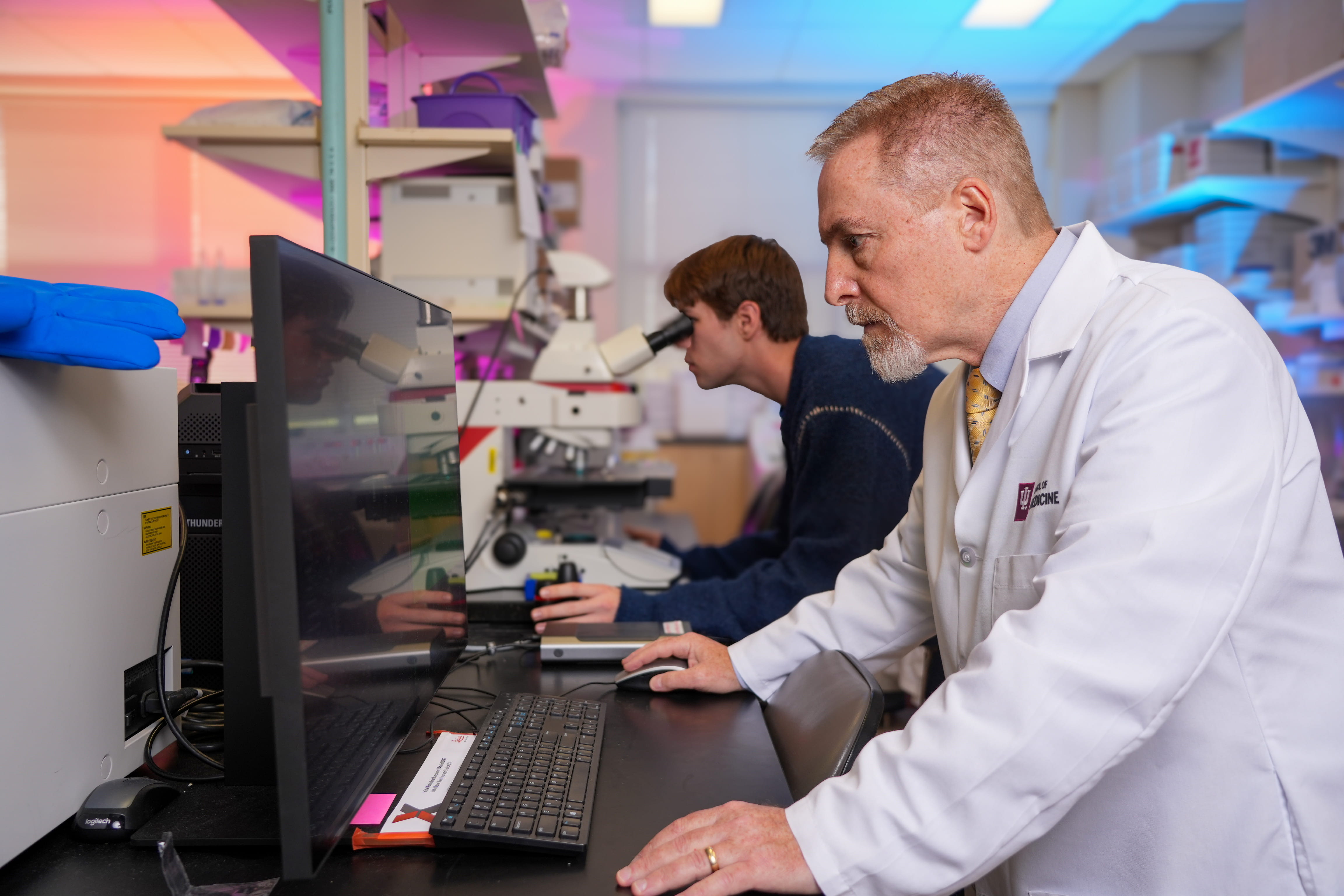 A man in a lab coat looks at a computer screen