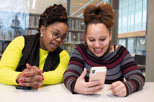 a community health worker and client look at photos of the client's son together on her phone