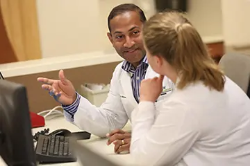 two physicians speak together in a clinical work space