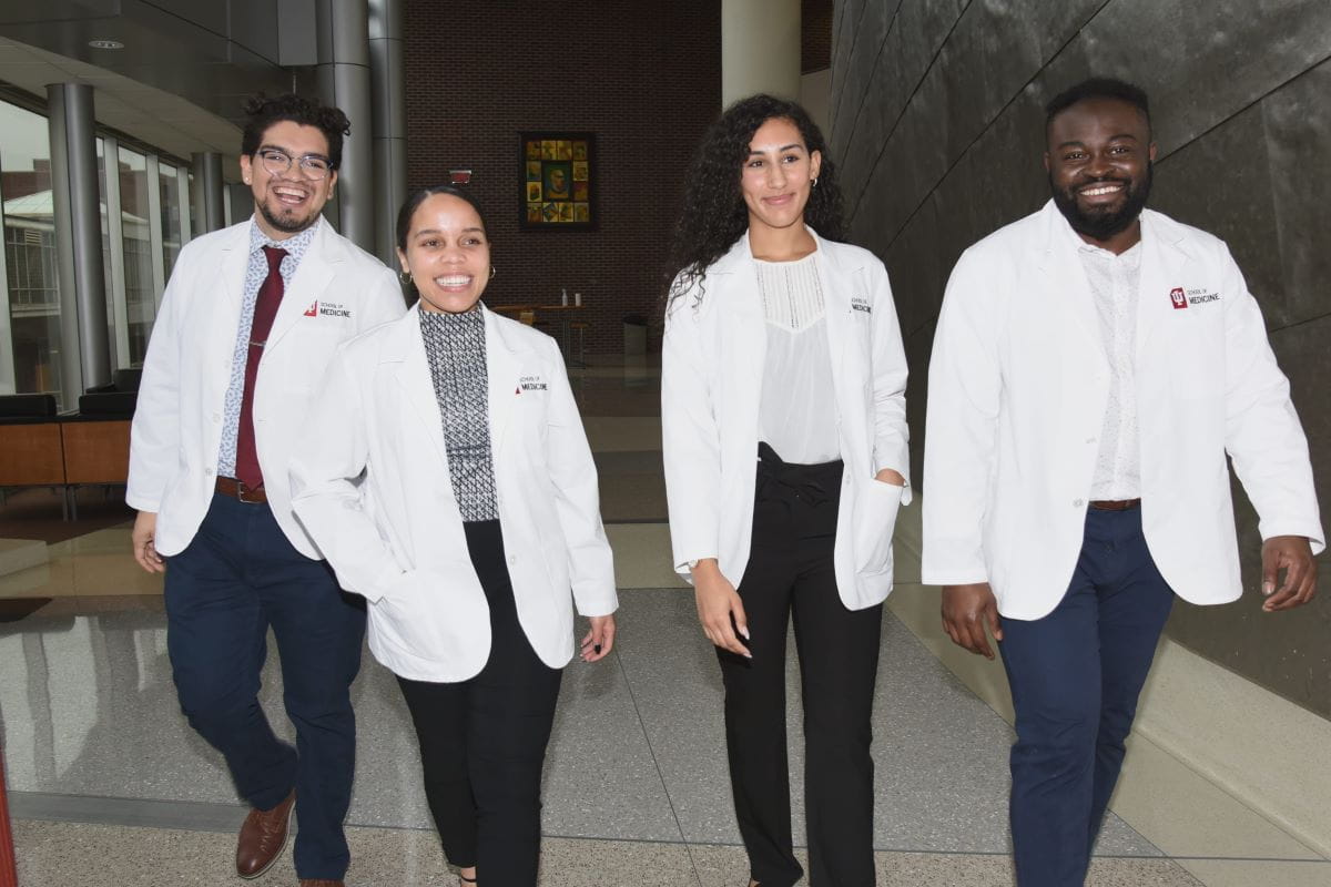 members of the dei coalition walk down the hall in their white coats