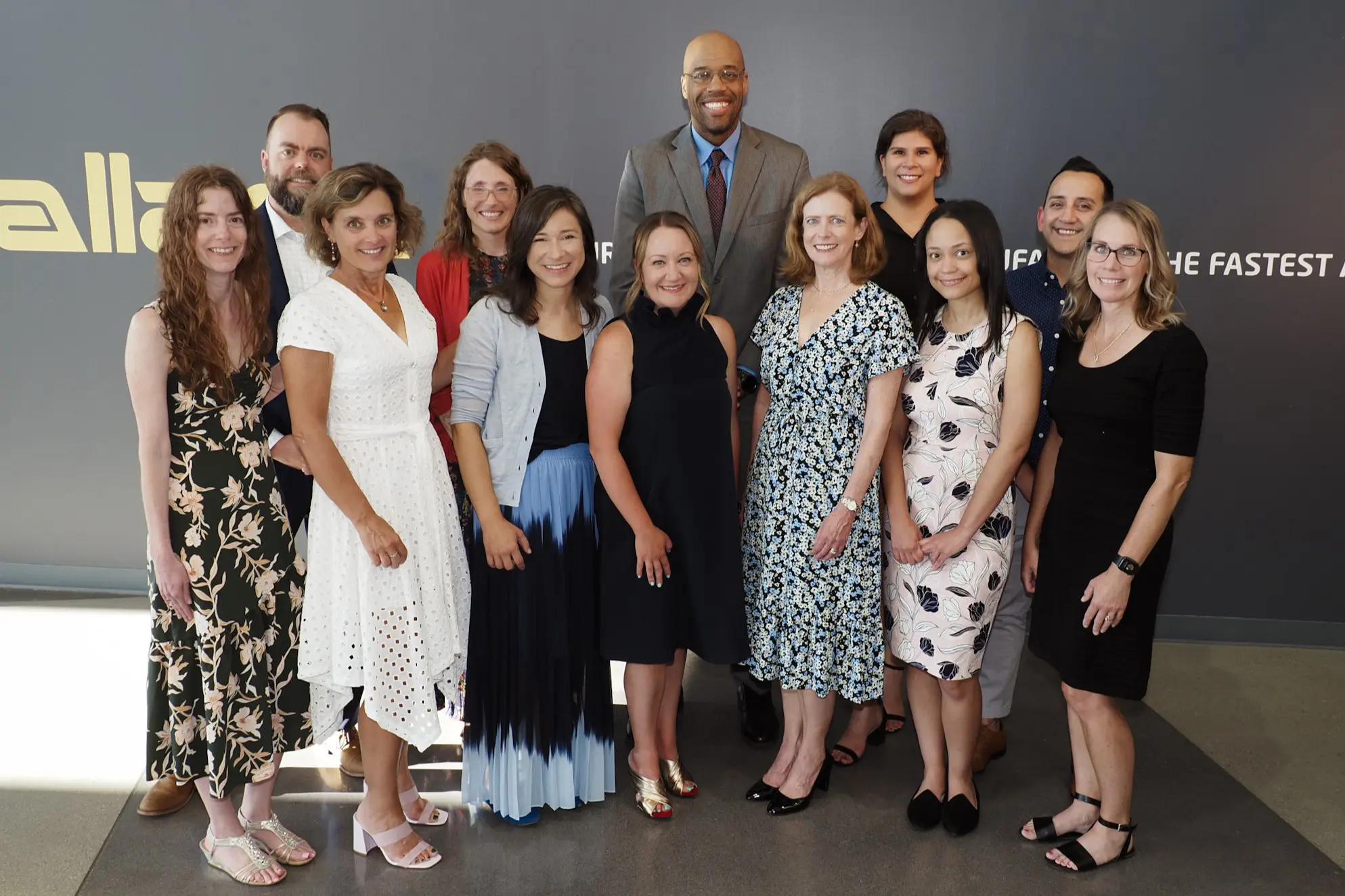 12 faculty members stand in front of a backdrop. 