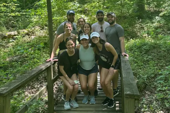 A group of nine residents hiking in the sunlit woods