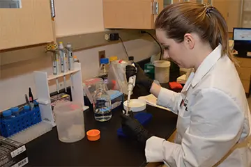 Researcher wearing a lab coat and working at a lab bench
