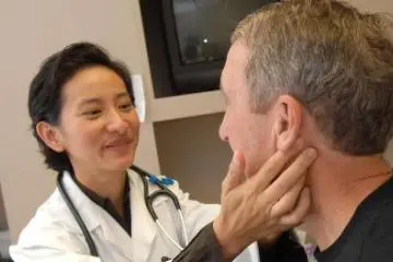 A physician feels the lymph nodes on the side of a patient's neck