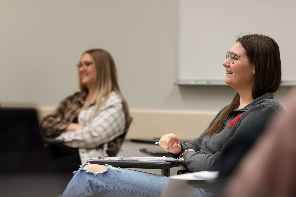 Two students in classroom listen to instruction