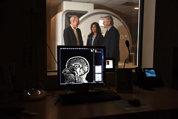 Three doctors chat next to a MRI.