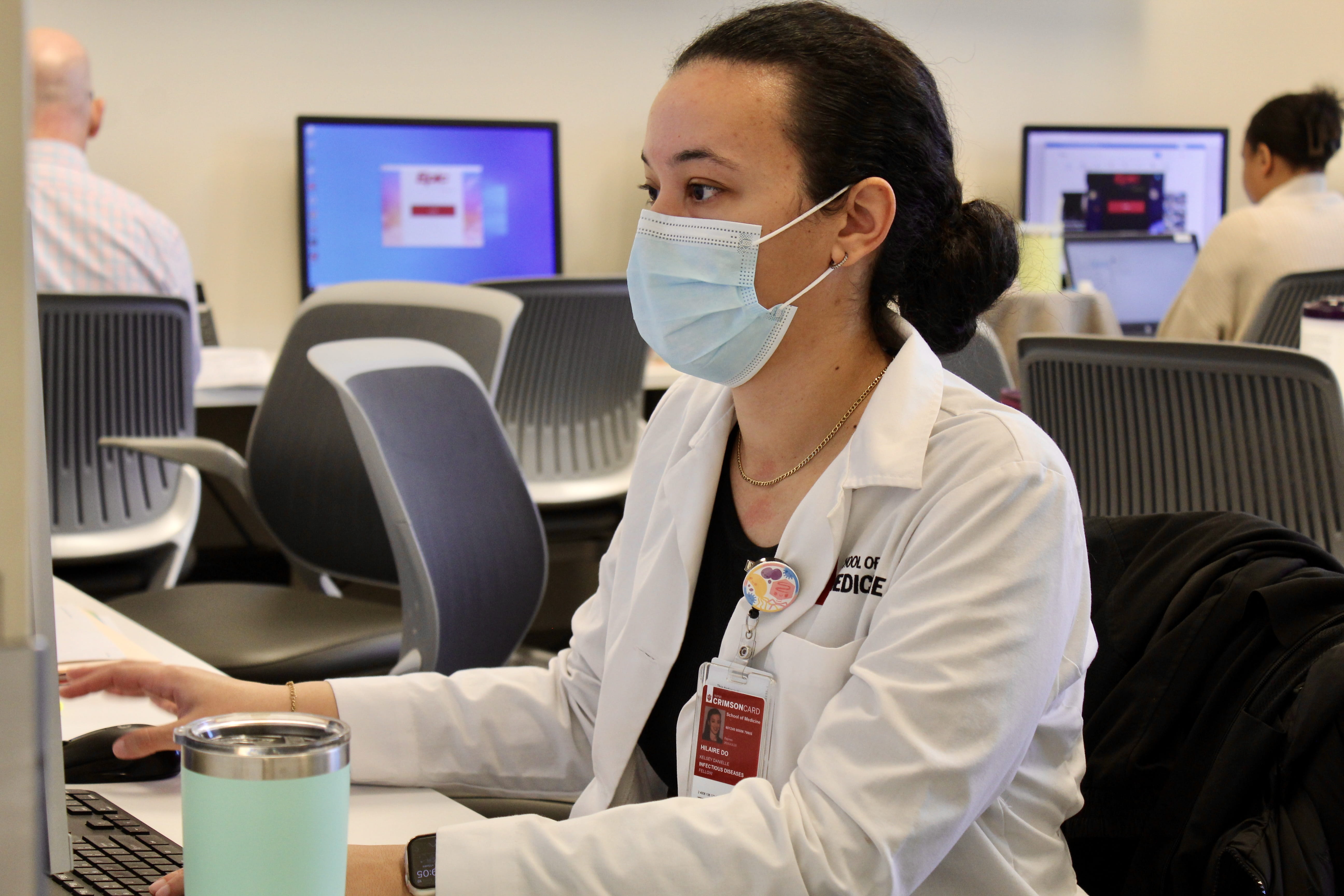 Picture OF Kelsey Hilaire, DO, wearing a mask doing clinical work