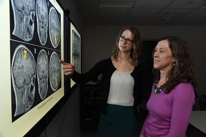 two researchers look at a brain scan on a large monitor