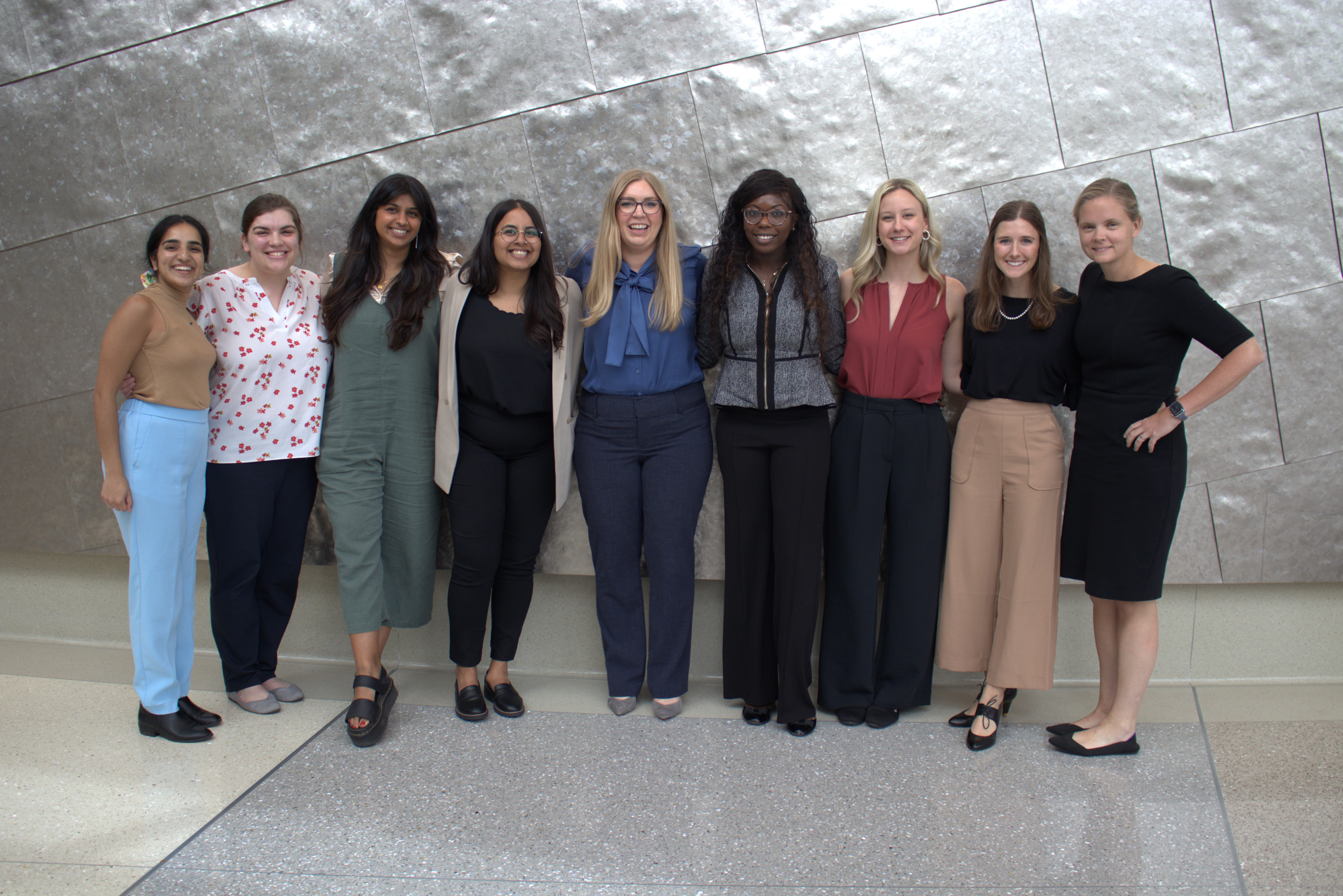 9 residents stand with director Nicole SCott, MD, after presenting their 3rd year research projects