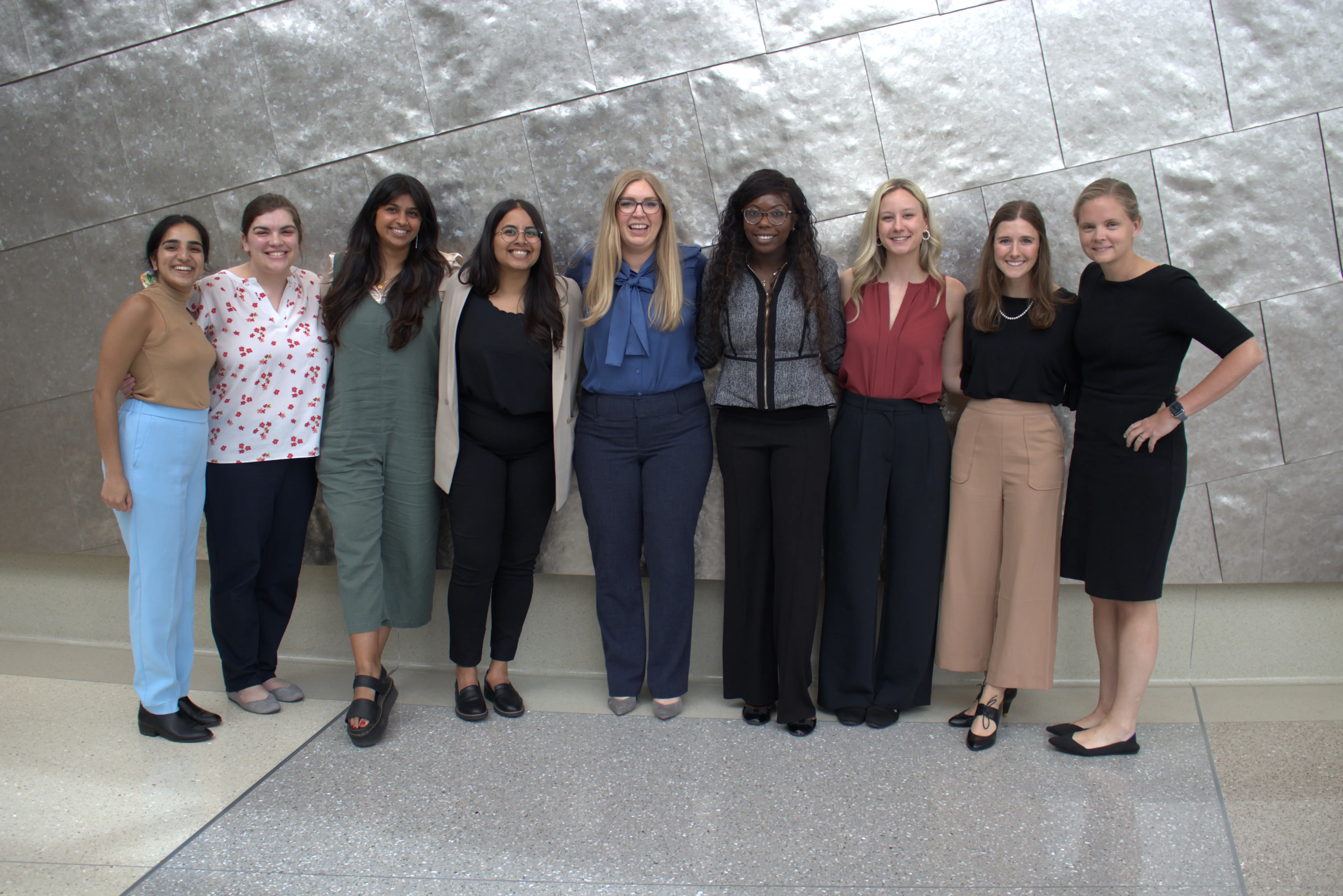 9 residents stand with director Nicole SCott, MD, after presenting their 3rd year research projects