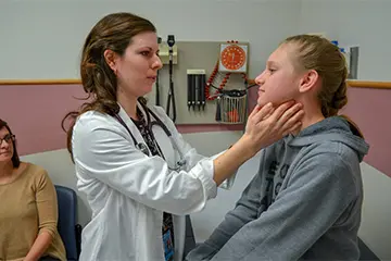 Physician checks pediatric patient's thyroids.