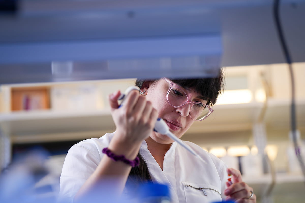 a graduate student prepares a sample in the lab