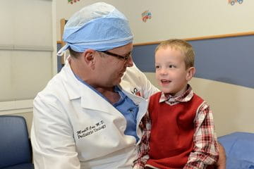 a physician in a white coat speaks with a young patient at riley hospital