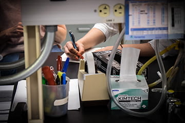 on a lab bench, a hand takes notes about an experiment