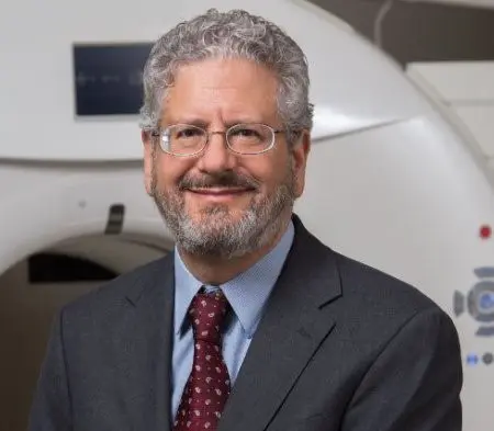 Andrew Saykin sits in front of an MRI machine