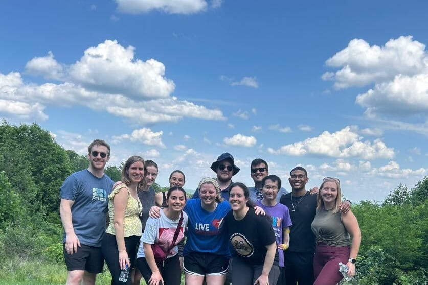 a large group of residents on a hike with cloudy blue sky overhead