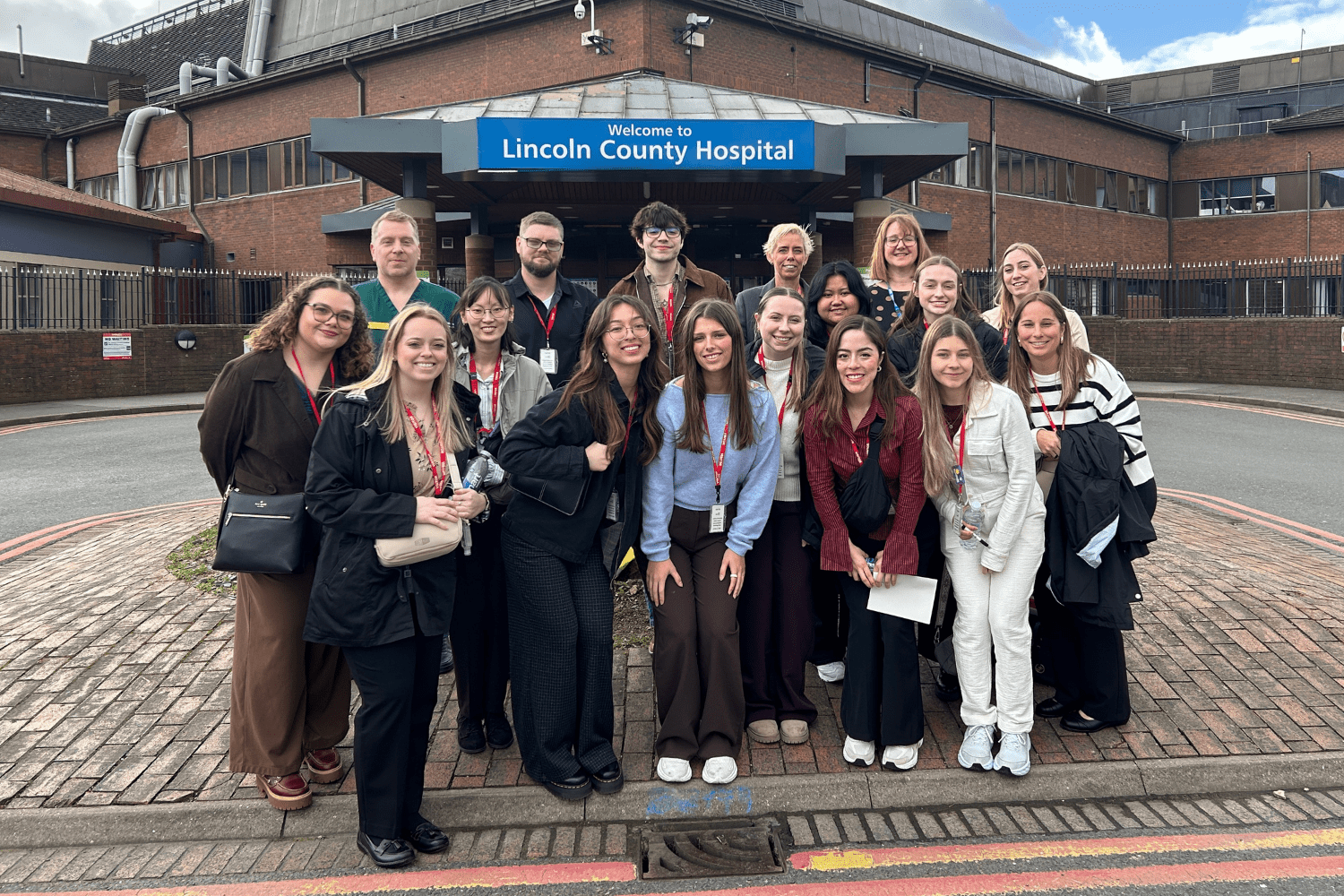 A group photo of students posing in front of the Lincoln County Hospital in London.