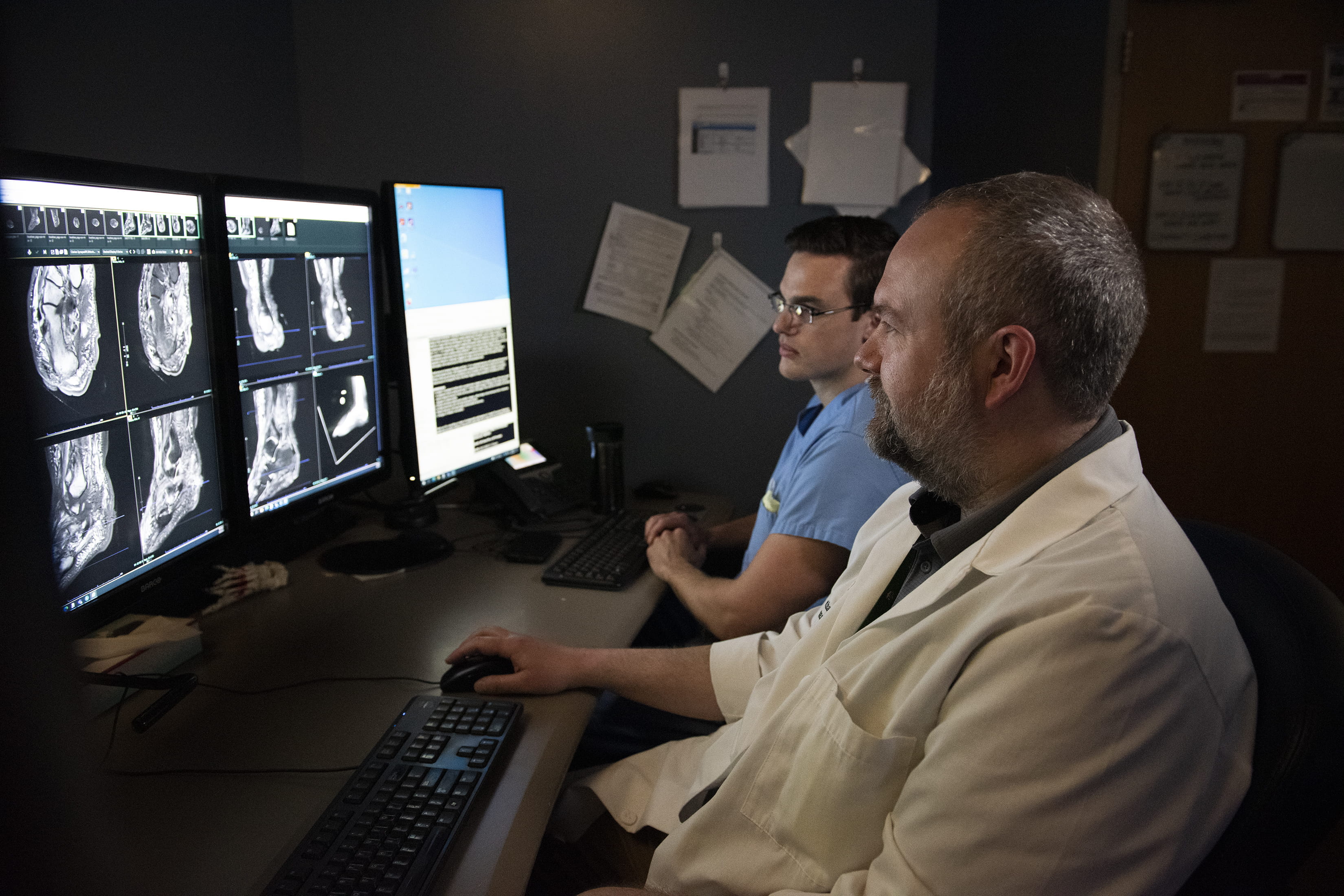 A male radiologist views musculoskeletal scan while a male trainee observes.
