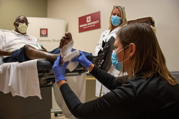 Researcher applies a wound dressing to a man's foot.