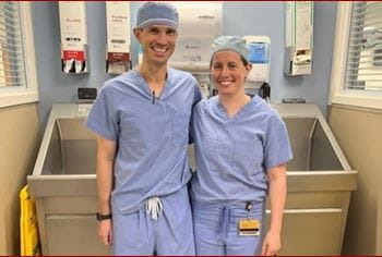 Tim Murphy and Michelle Lawson. | Photo courtesy Michelle Lawson Orthopaedic Surgery Trauma fellows, Tim Murphy and Michelle Lawson, pose in their surgical scrubs in front of the sink where they scrub in.