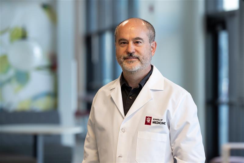 A man (Tim Richardson) with close cropped gray hair and an IU School of Medicine lab coat in the laboratory setting.