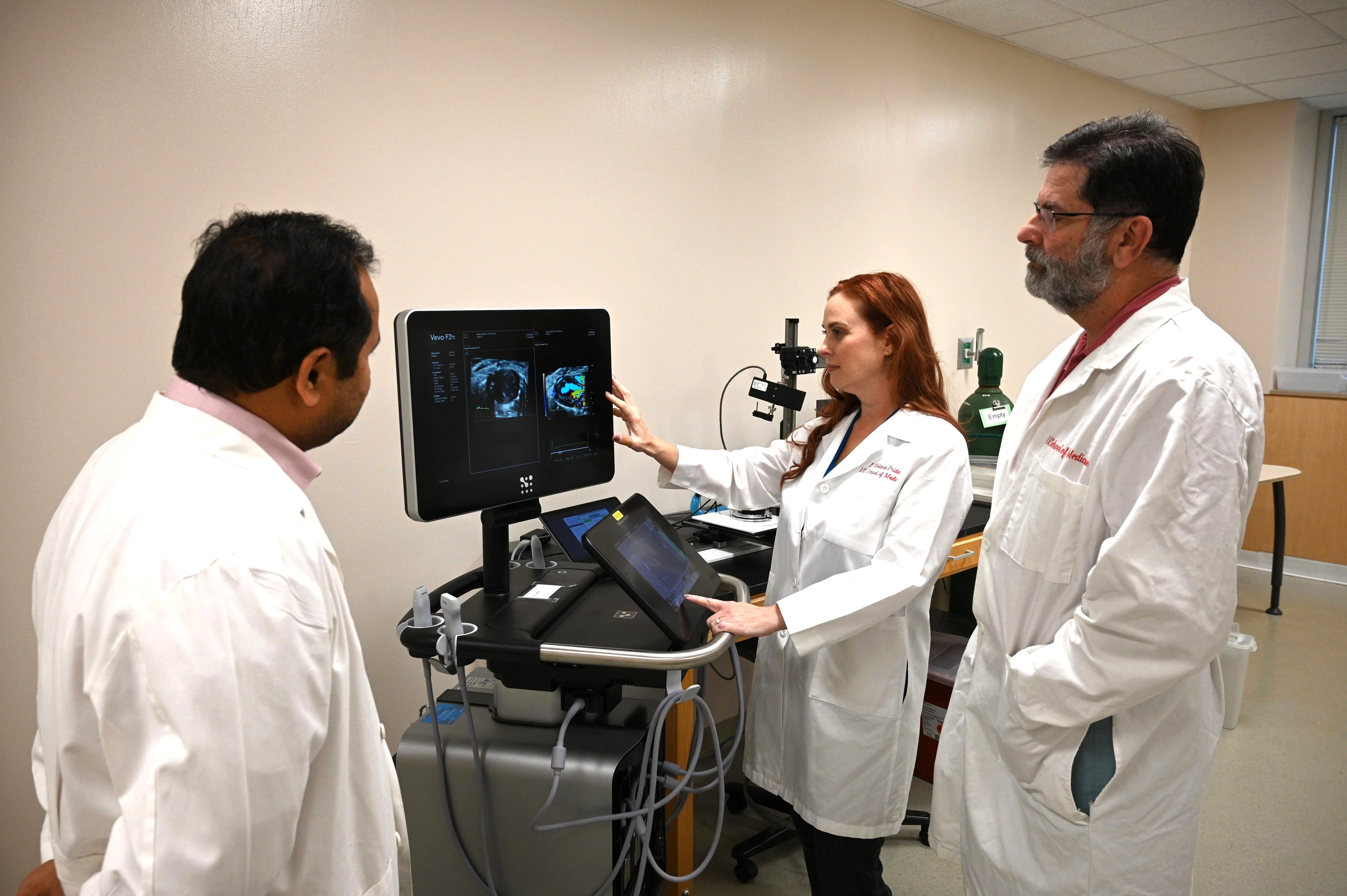 Three people from the Medical Imaging Research Institute glance at the monitor of a new ultrasound system.