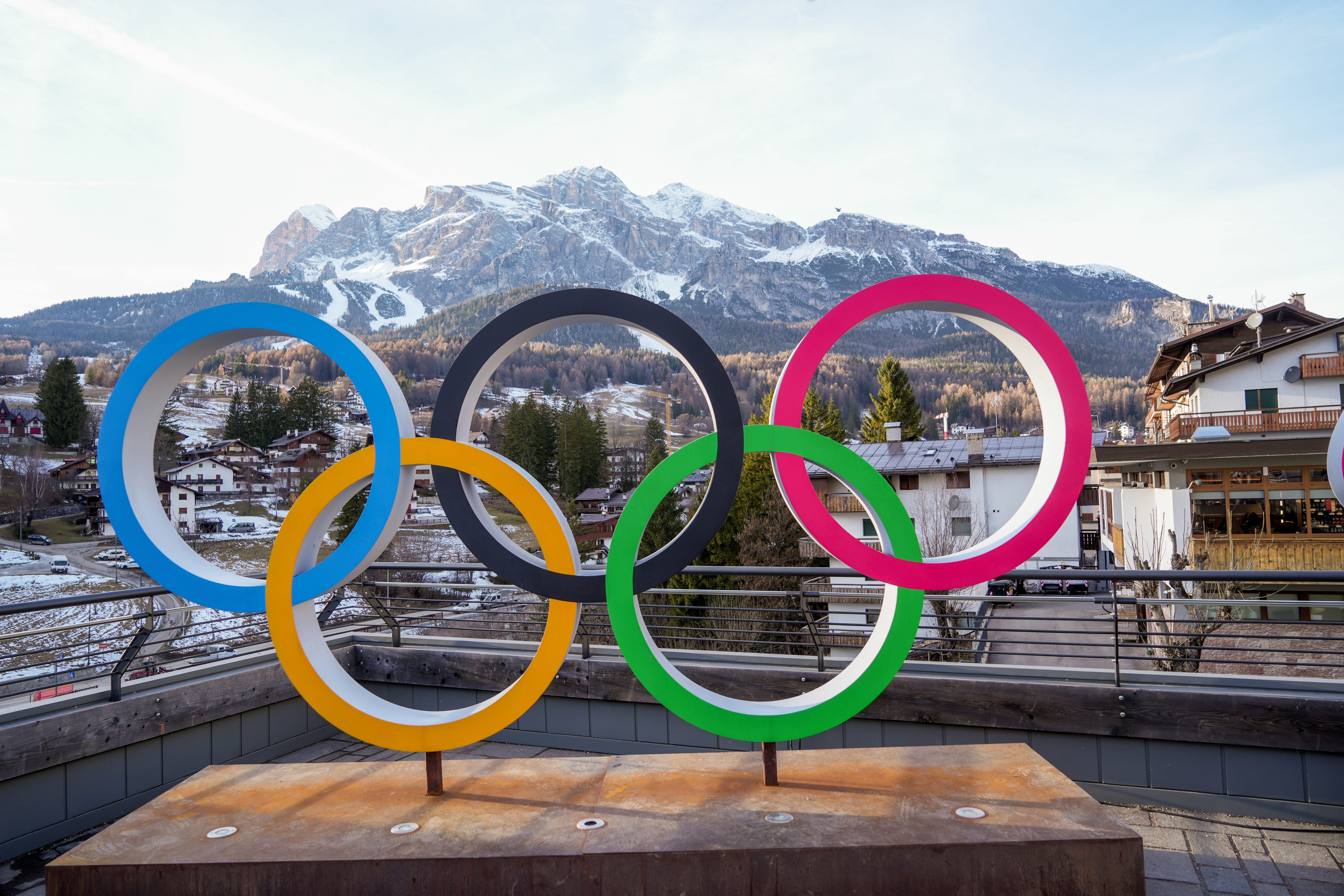 picture of olympics logo with mountain behind it and buildings 